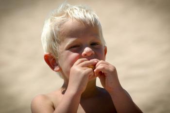 Niño comiendo fruta en la playa