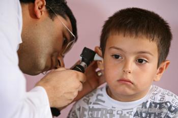 Pediatra explorando la audición de un niño en la consulta