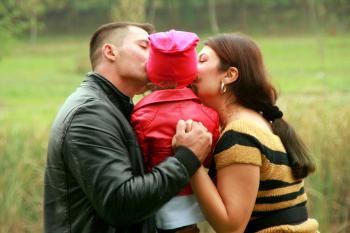 Padre y madre dando un beso a su hija