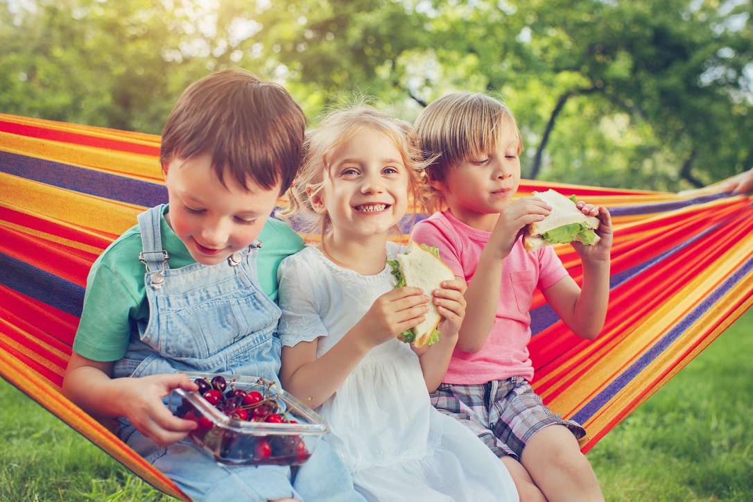 Niños merendando en una hamaca al aire libre