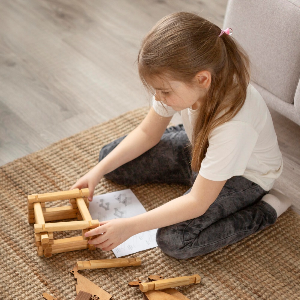 Niña jugando en el suelo con piezas de madera