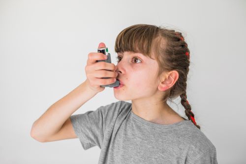 Niña con asma utilizando un inhalador