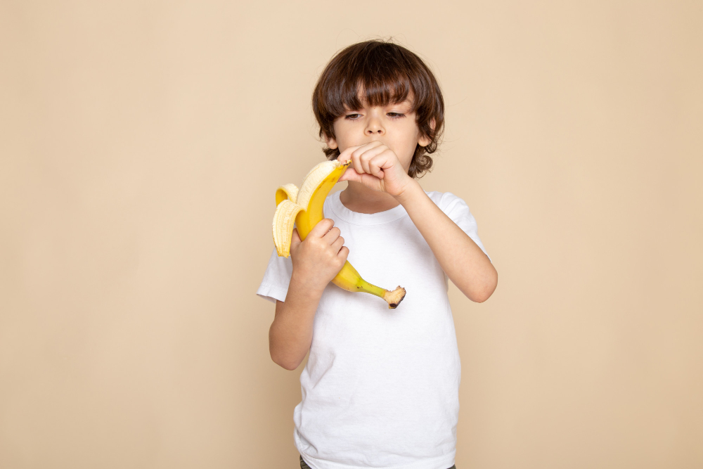 Niño comiendo plátano. Freepik