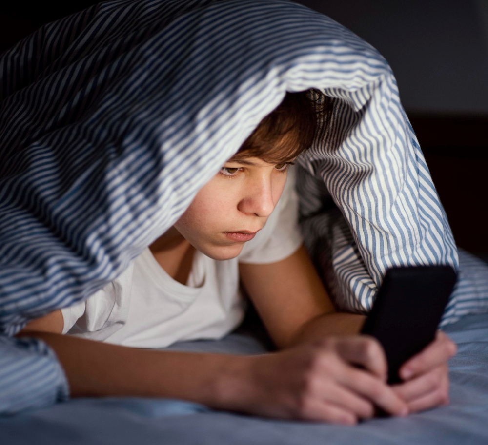 Niño en la cama a oscuras con el móvil