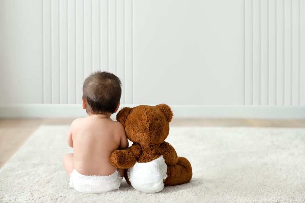 Niño sentado con su osito de peluche en el suelo