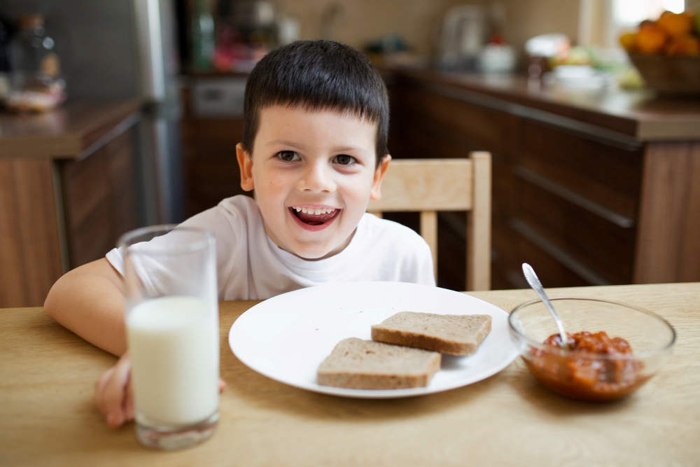 Niño desayuna tostadas con leche