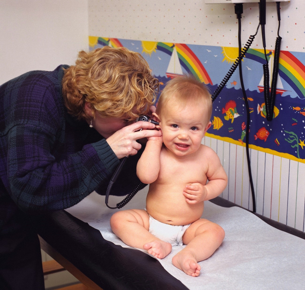 Bebé en el pediatra mirando oído