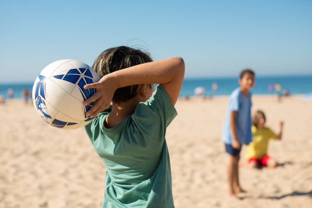 Nens jugant al futbol a la platja en estiu