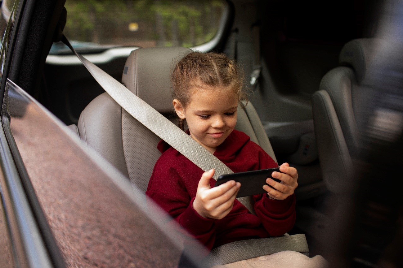Nena al cotxe mirant el mòbil