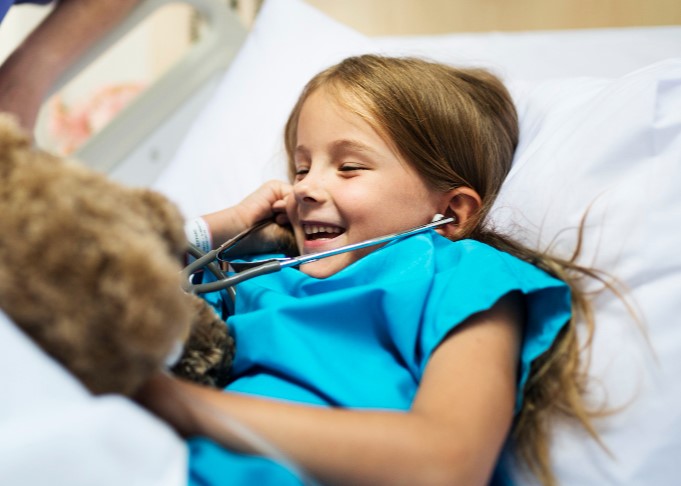 Niña en una cama de hospital riendo. Freepik