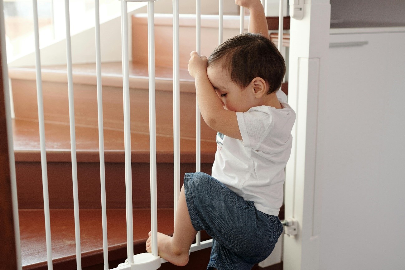 Niño intentado trepar por la barrera de seguridad de las escaleras