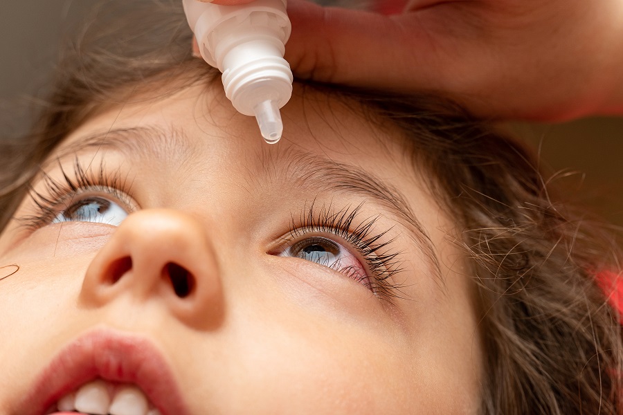 Niño echándose gotas en el ojo por la conjuntivitis - Imagen de adobe stock