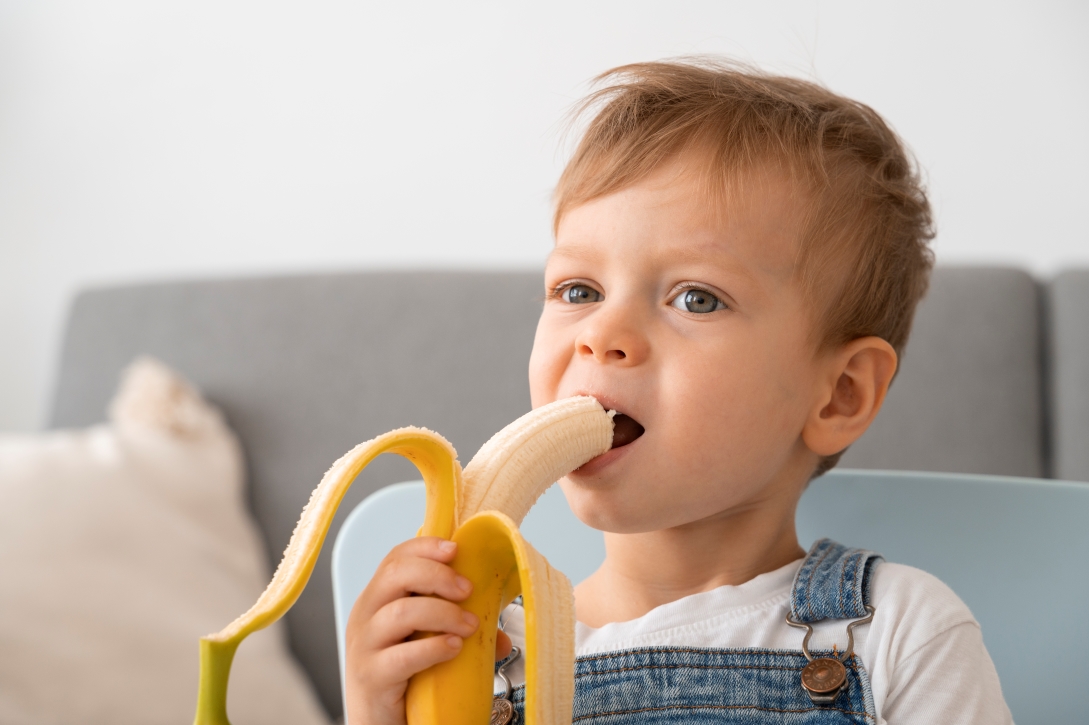 Niño pequeño come un plátano