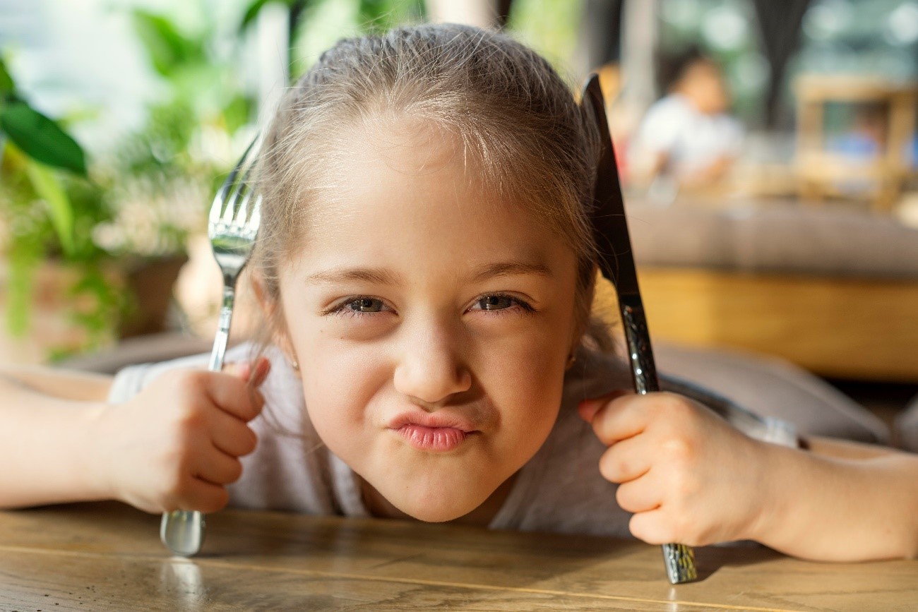 Niña con hambre en el restaurante