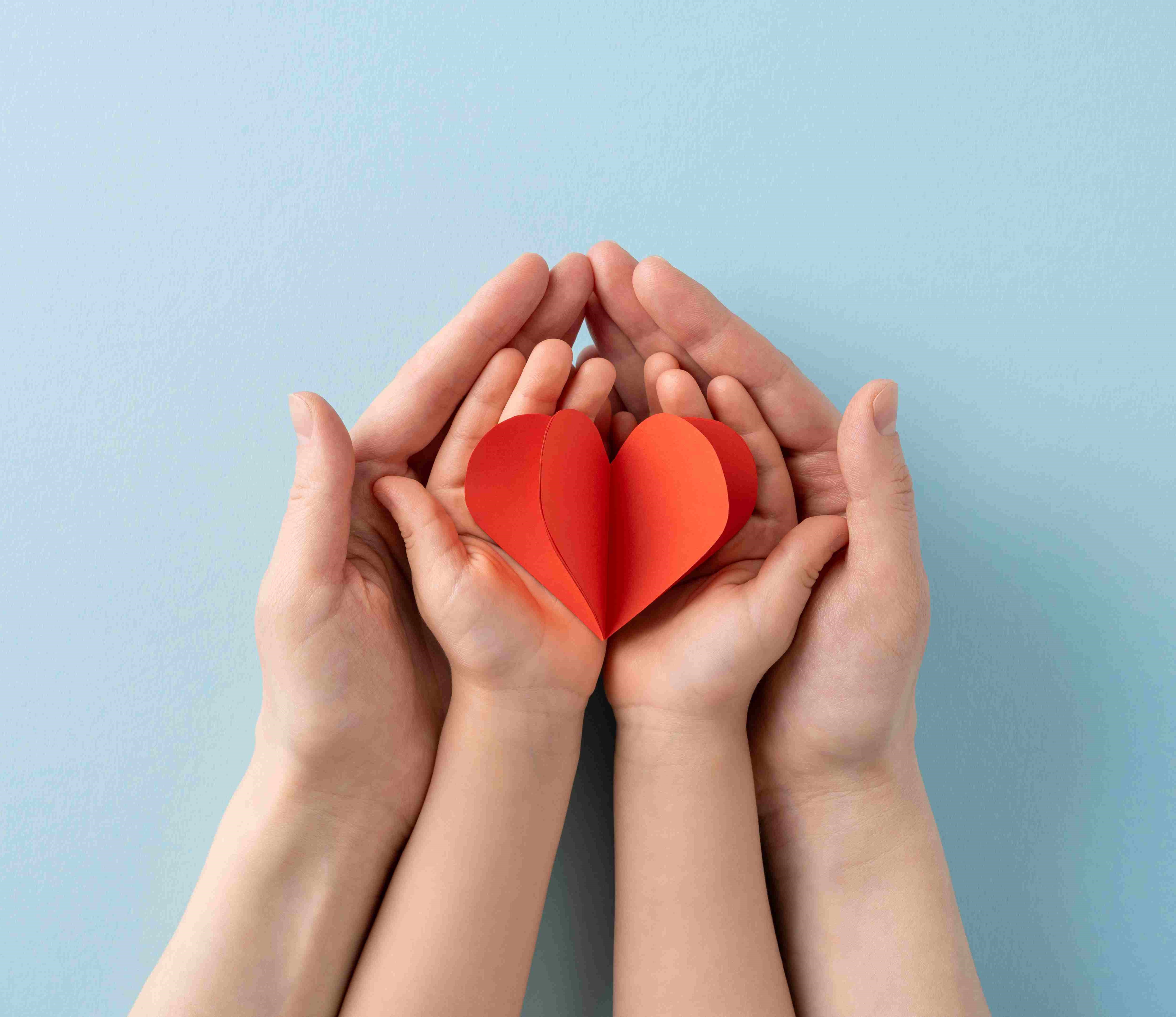 corazon de papel en manos de niño y adulto