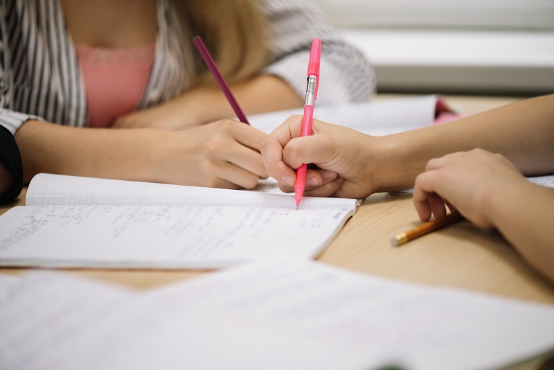 detall d'alumnes escrivint en llibreta